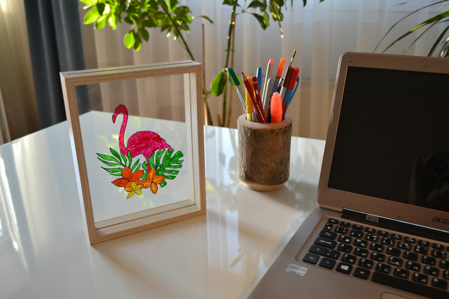 Laptop i flaming na białym biurku.